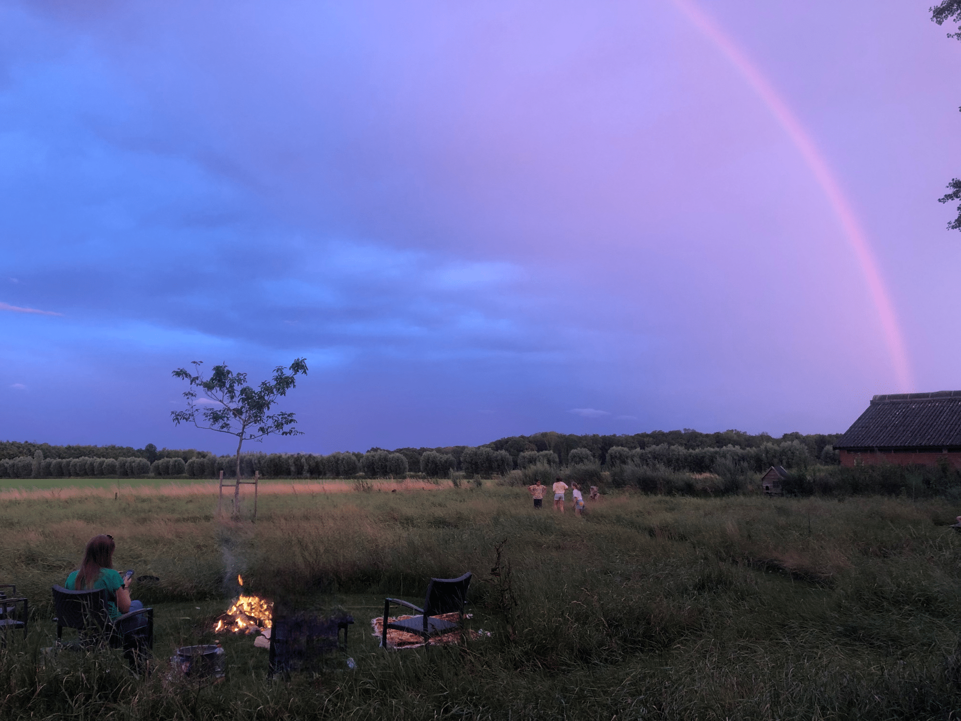 Een regenboog boven het veld bij IJsselgoud, met kampvuur in de avond